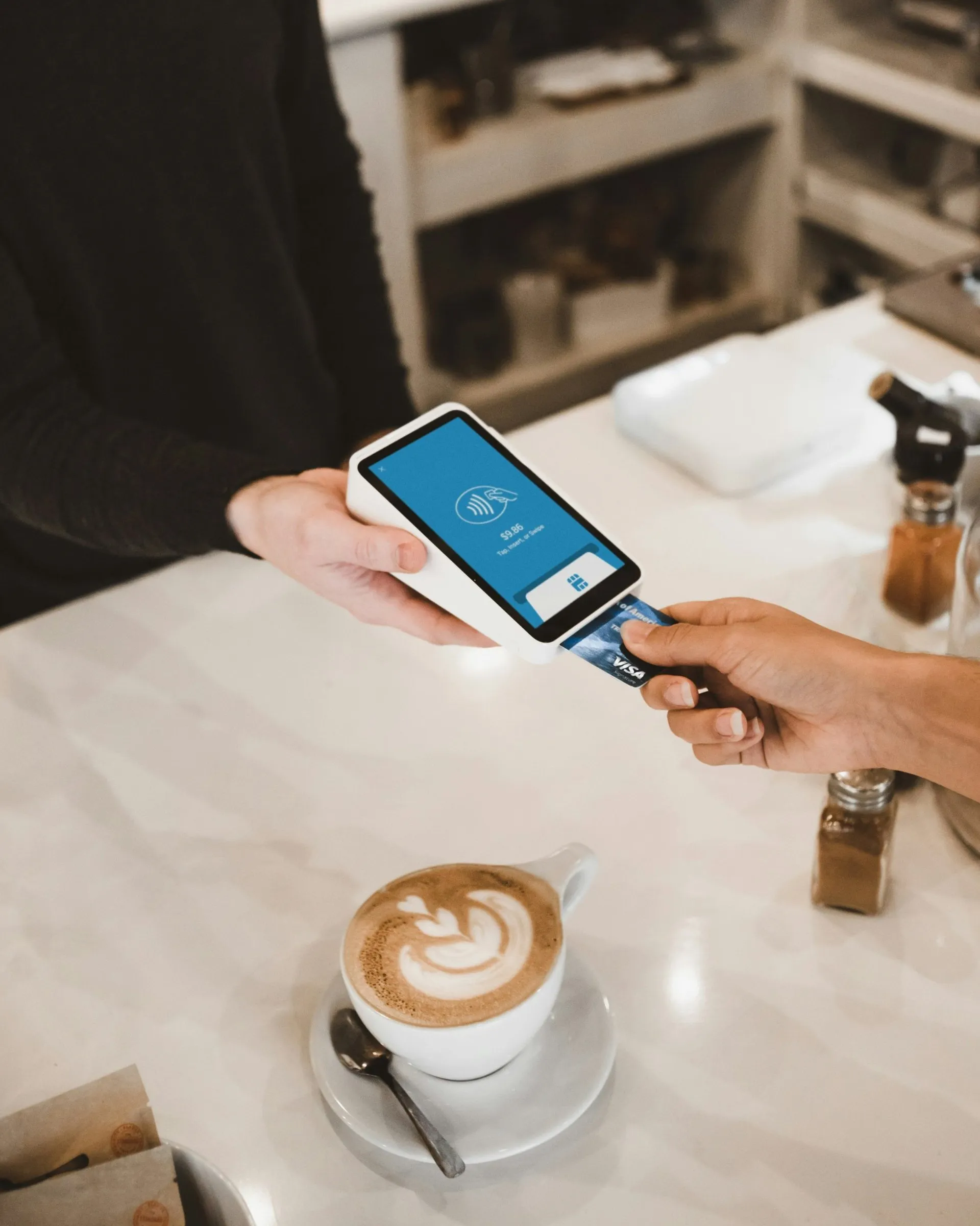 A customer paying with a Visa card at a café payment terminal